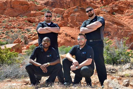 Four men posing in front of rocks