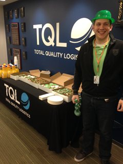 Man with St. Patcricks Hat next to table of doughnuts