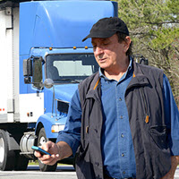 Truck driver using TQL Carrier Dashboard on his mobile device.